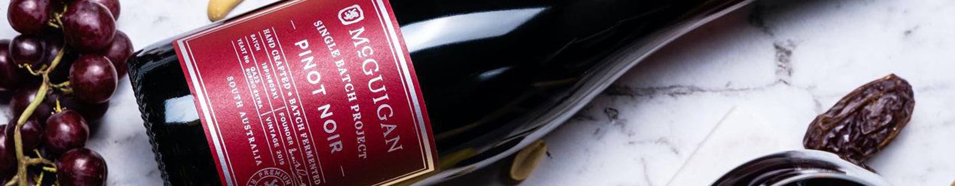 bottle of red wine with fruit next to it